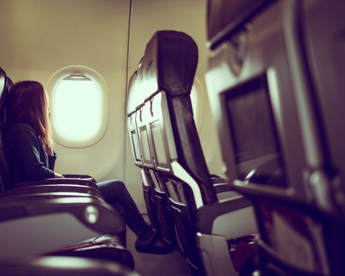 vue-laterale-d-une-femme-voyageant-dans-un-avion-assise-pres-de-la-fenetre-min vue-laterale-d-une-femme-voyageant-dans-un-avion-assise-pres-de-la-fenetre-min